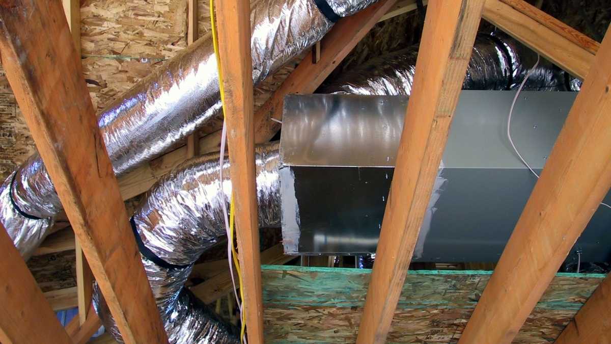 Attic view of HVAC ductwork with shiny insulation, surrounded by wooden beams.

The space appears under construction, conveying industrial functionality.