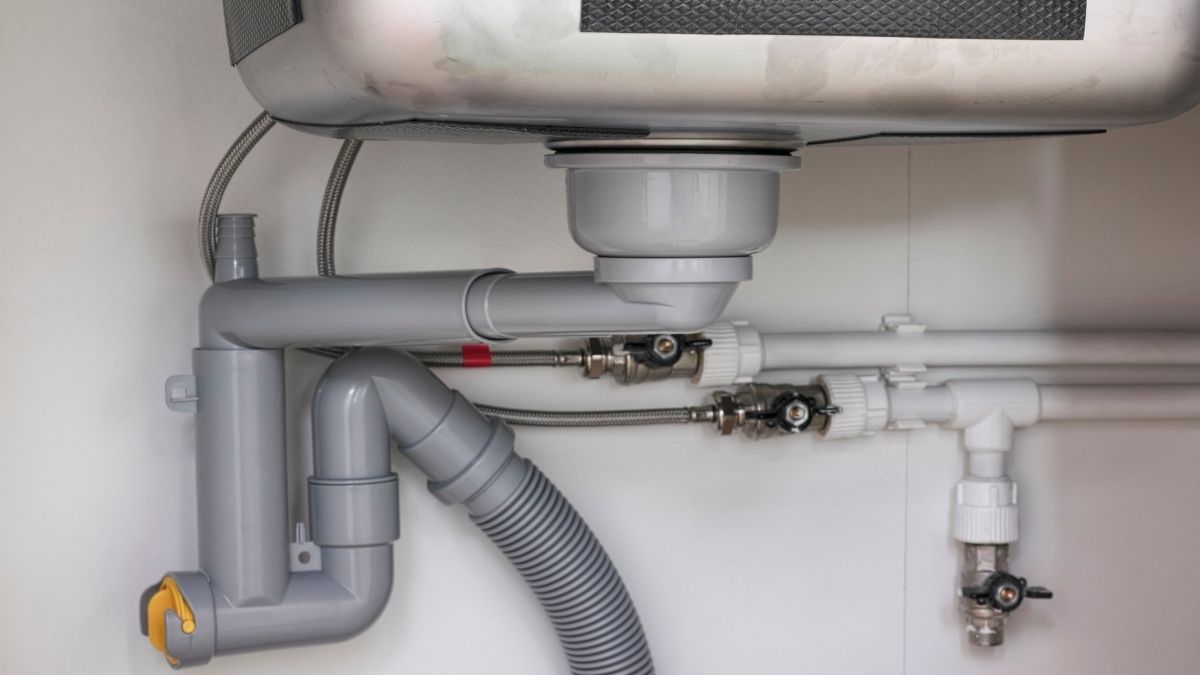 Under-sink plumbing with gray PVC pipes and a flexible drain hose.

Metal connector valves are visible, indicating a tidy installation.